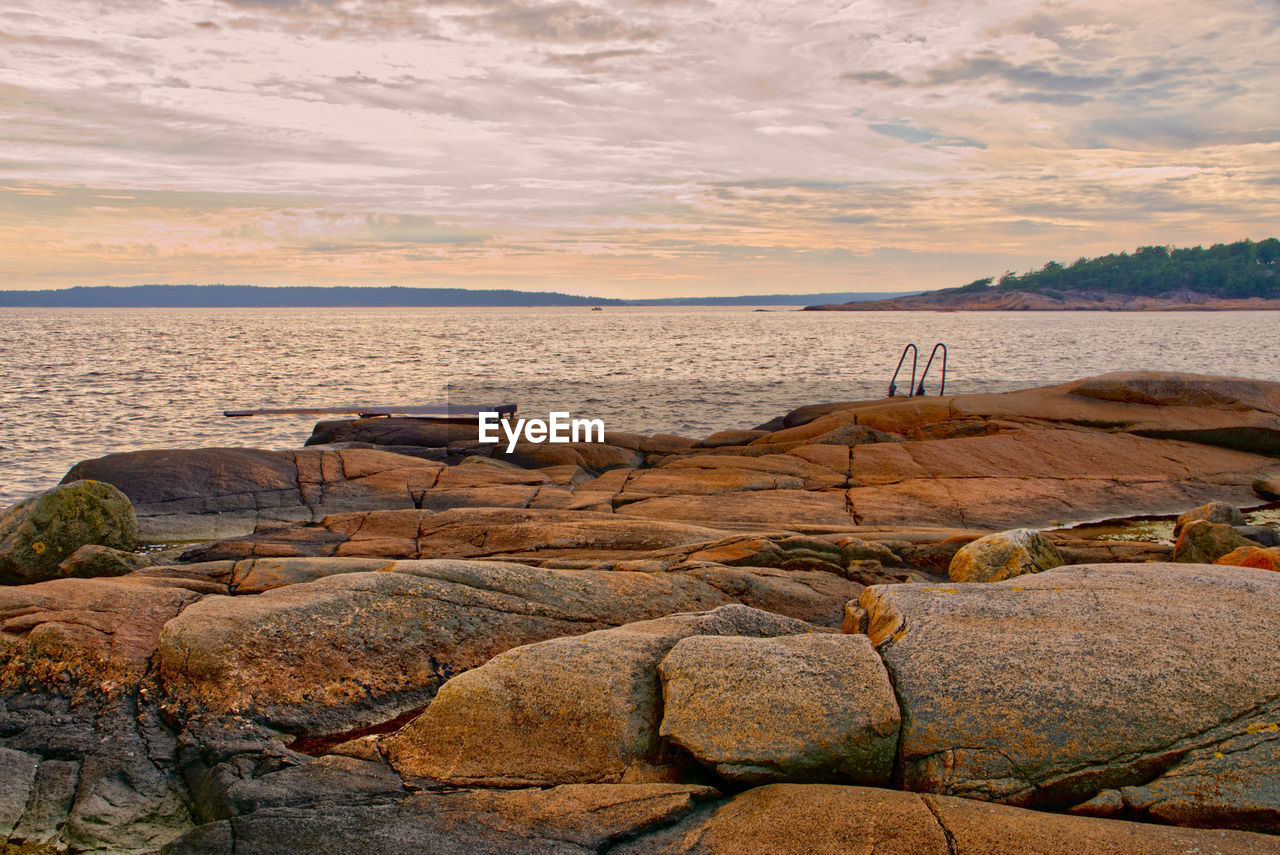 A rocky beach late on a summer day host a diving board and ladder for extra fun 