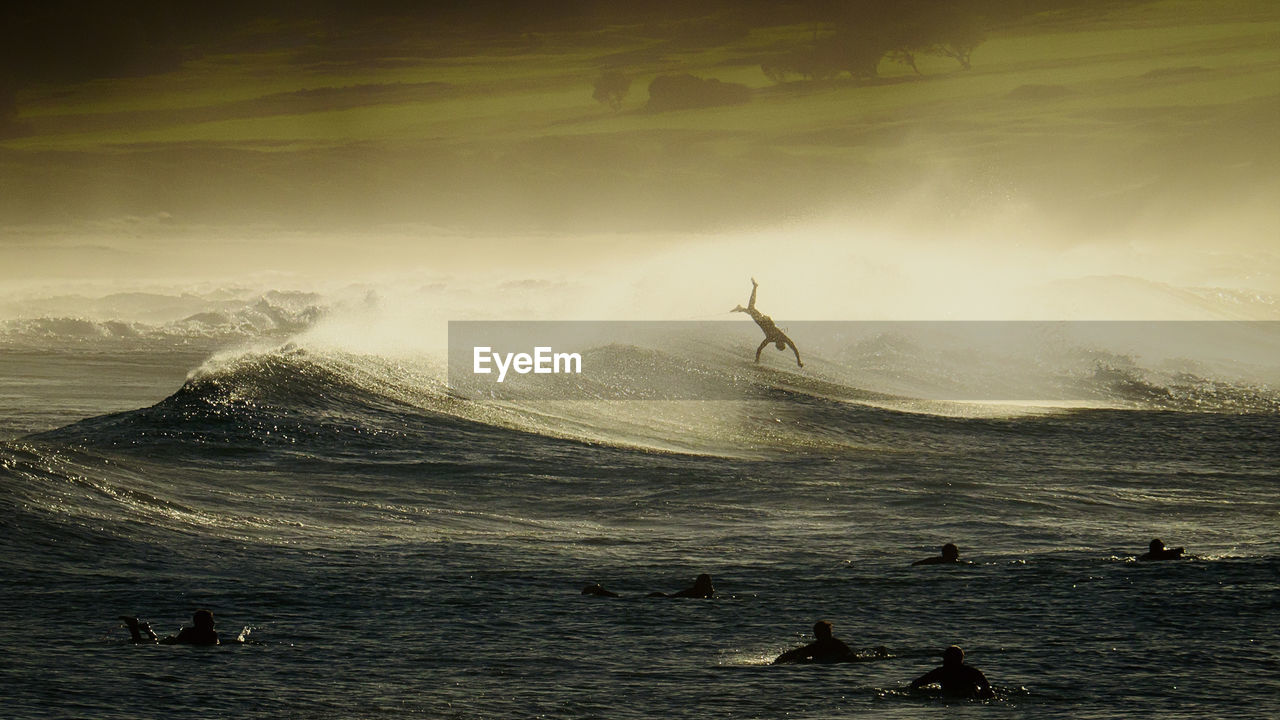 Silhouette man surfing in sea against sky