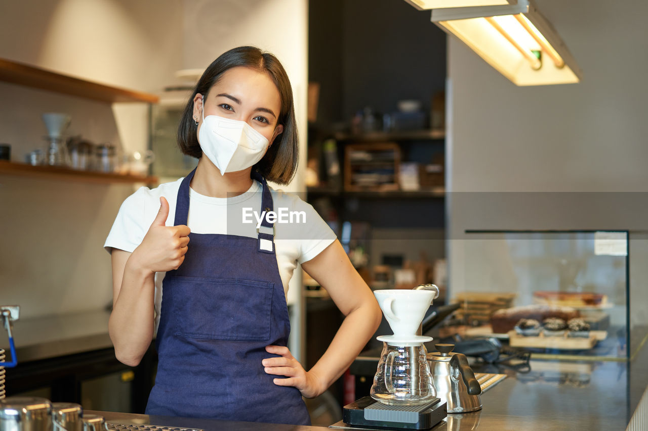 portrait of young woman drinking water in kitchen