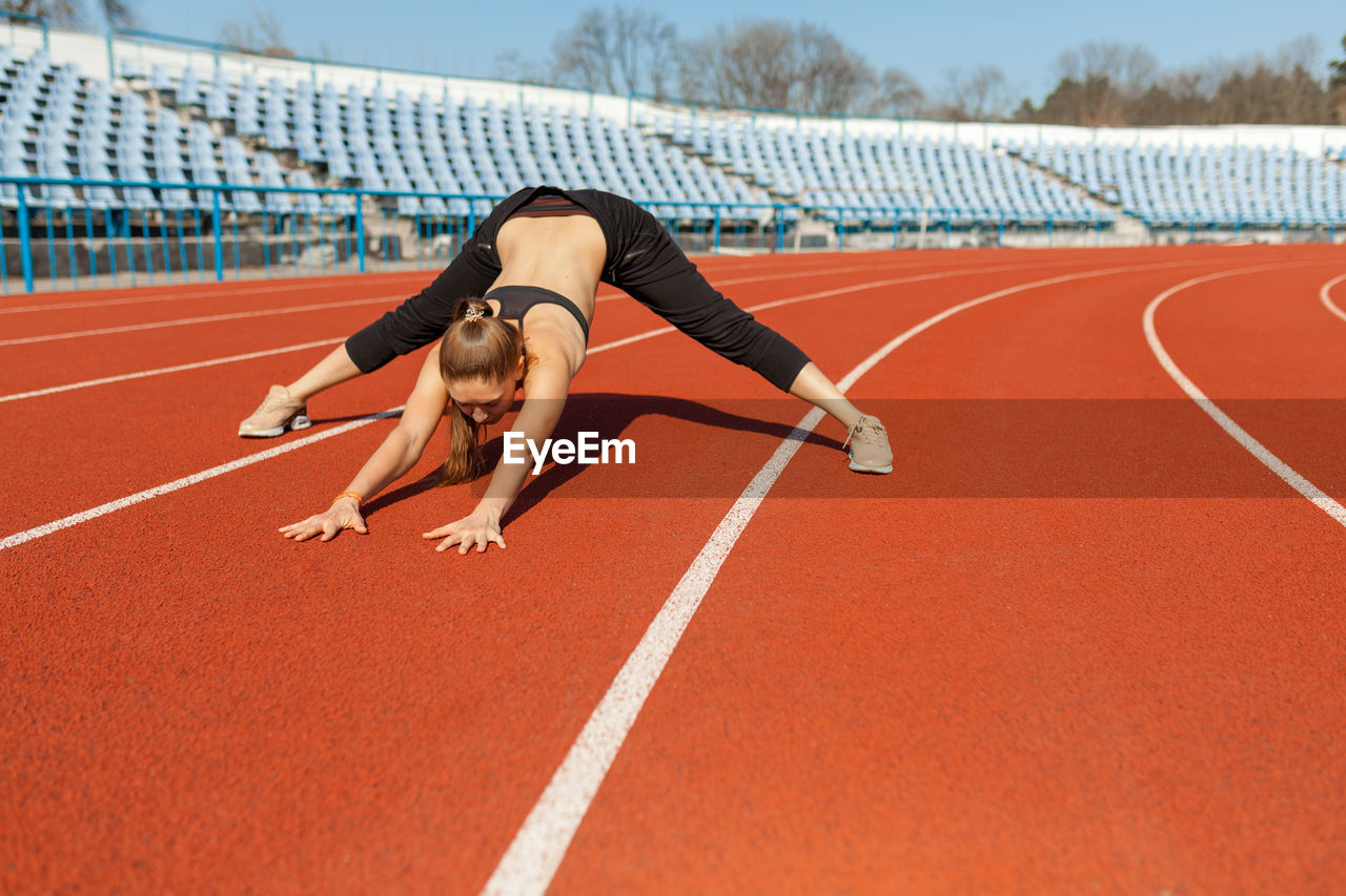 Full length of woman exercising on stadium