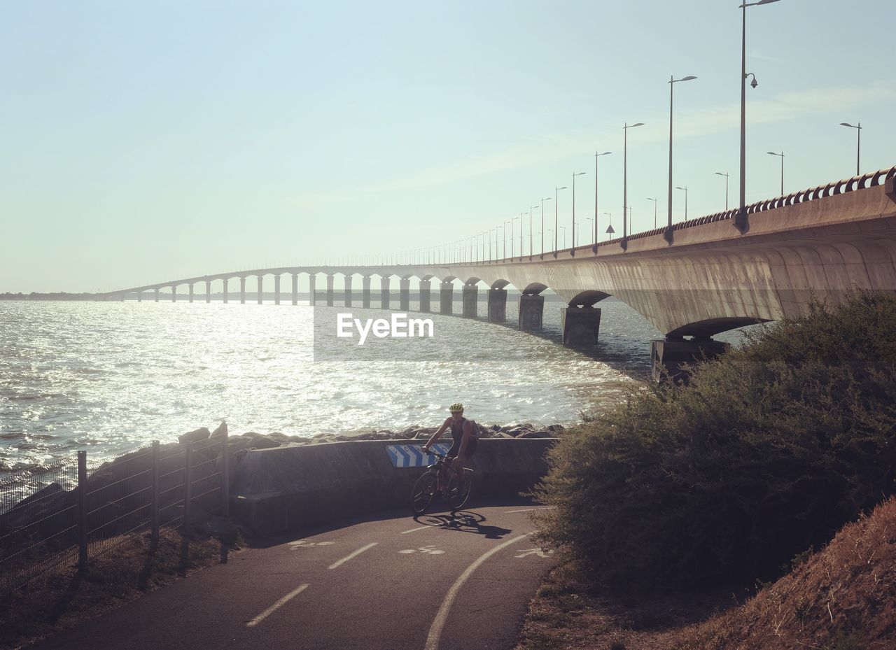 Bridge over calm sea against sky in city