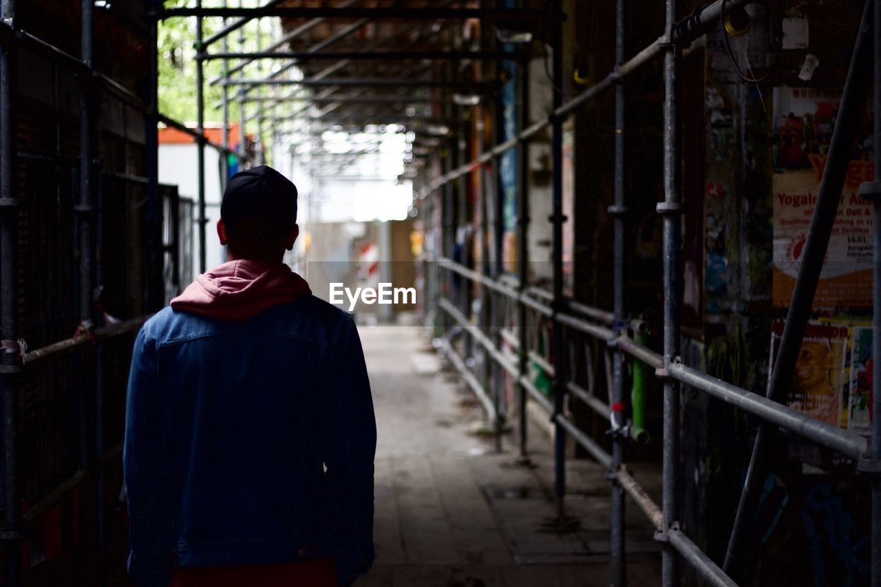 Rear view of man on street through construction site
