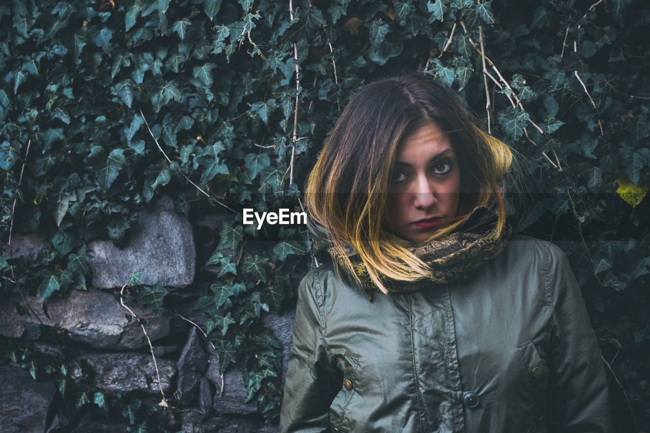 Portrait of beautiful young woman against trees