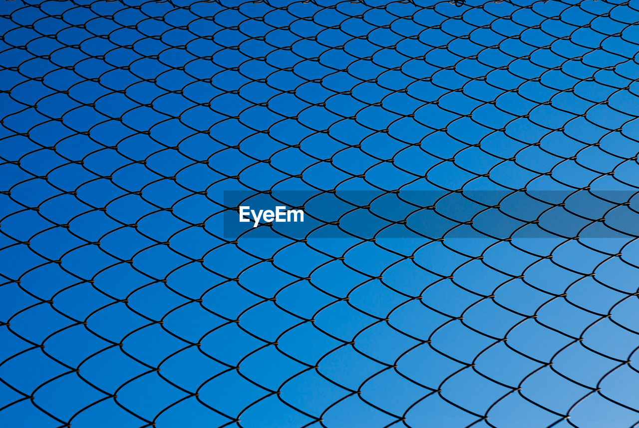 Full frame shot of chainlink fence against blue sky