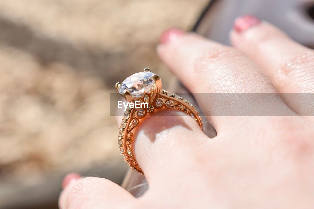 CLOSE-UP OF HUMAN HAND HOLDING RING