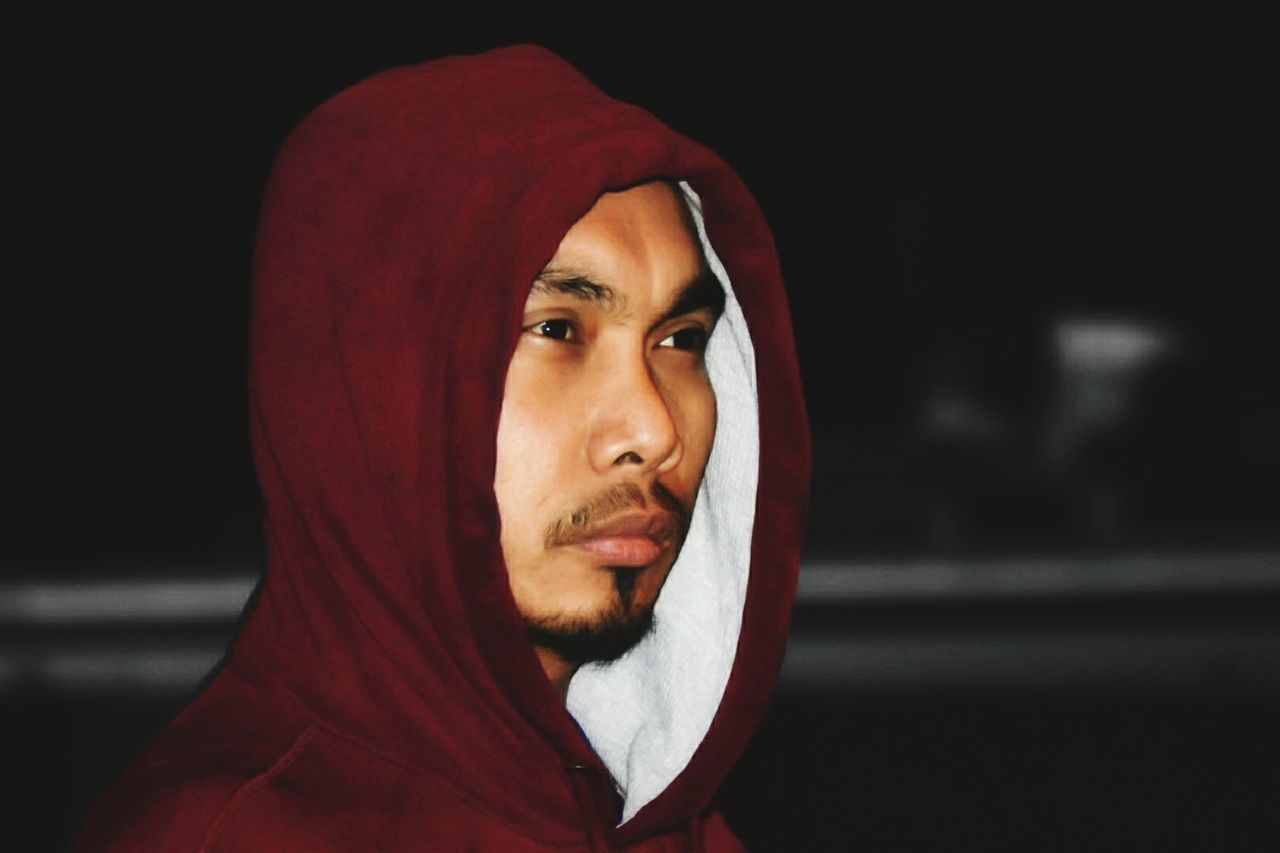 Hooded young man looking away at night