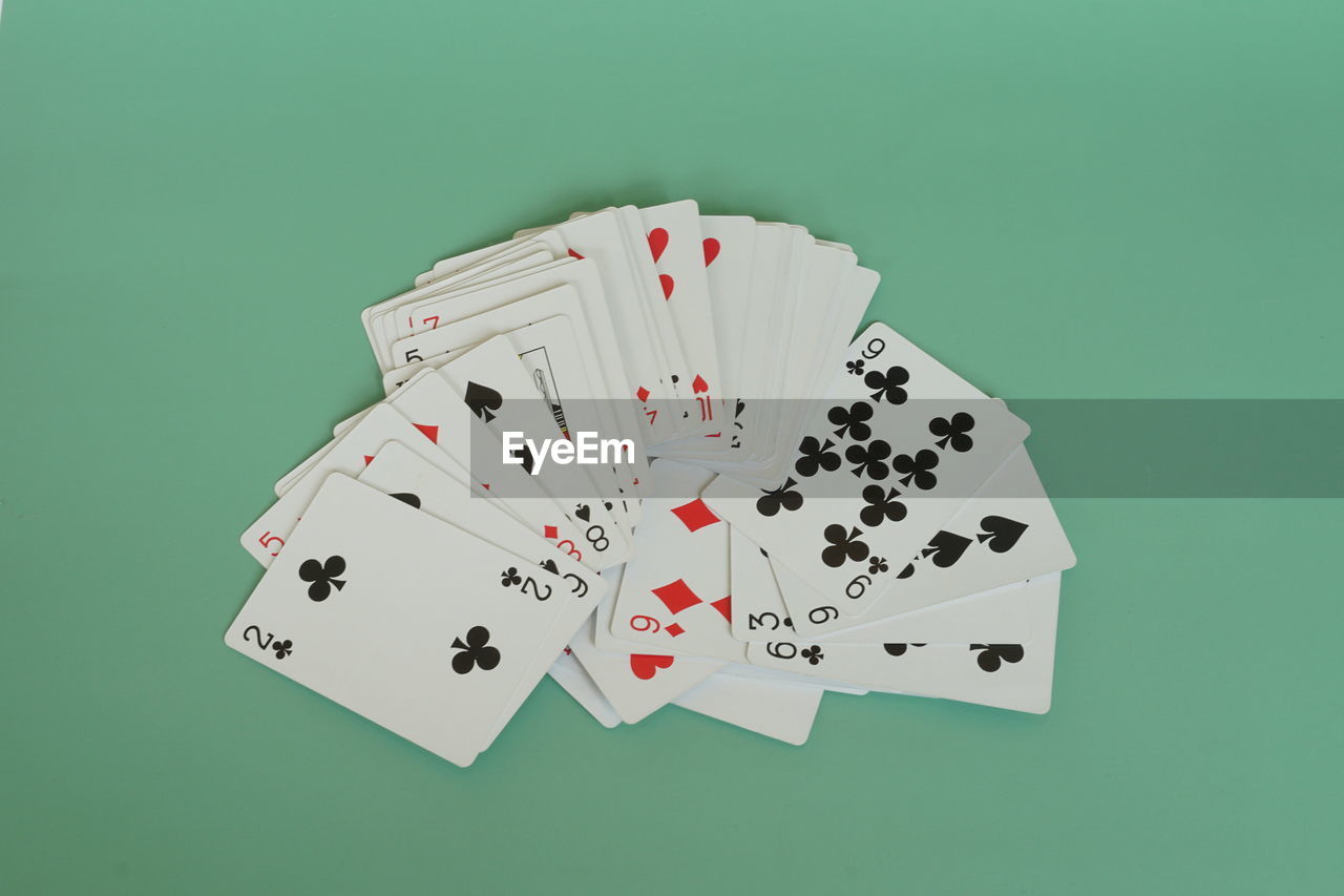 gambling, cards, leisure games, luck, game, arts culture and entertainment, poker, opportunity, card game, relaxation, leisure activity, recreation, green background, colored background, casino, risk, no people, studio shot, indoors, success, winning, large group of objects, high angle view