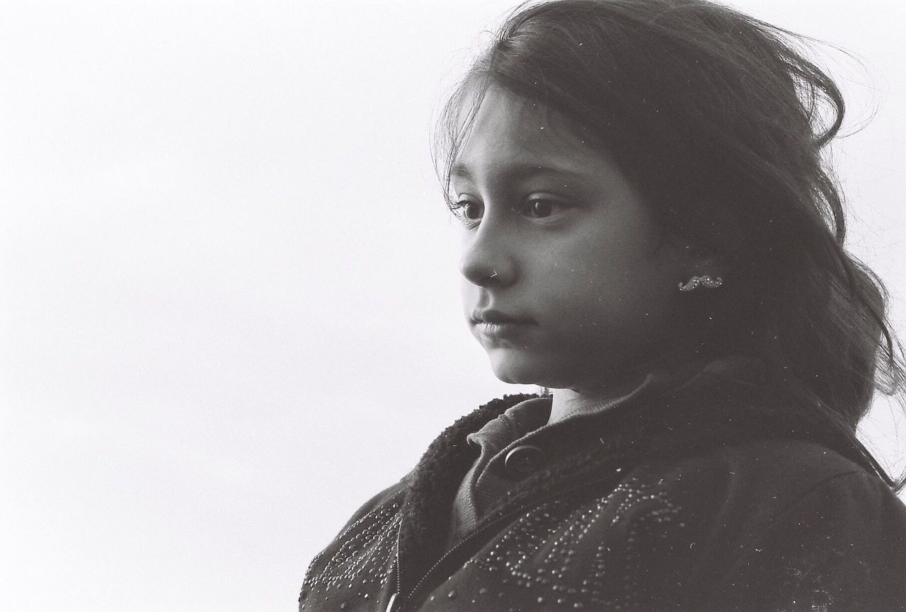 PORTRAIT OF YOUNG WOMAN LOOKING AWAY OVER WHITE BACKGROUND