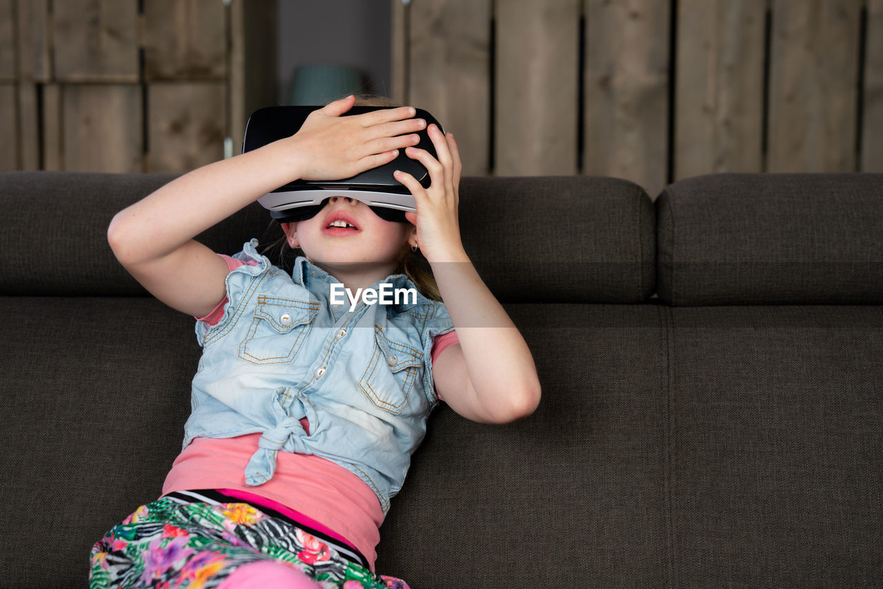 Girl wearing virtual reality simulator in home