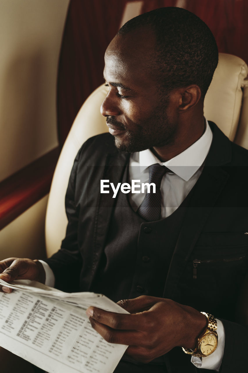 Businessman with newspaper looking away in private jet