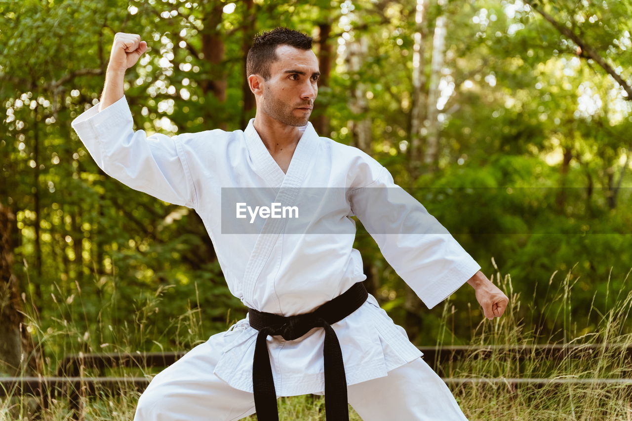 Man with karategi practicing martial arts in the forest