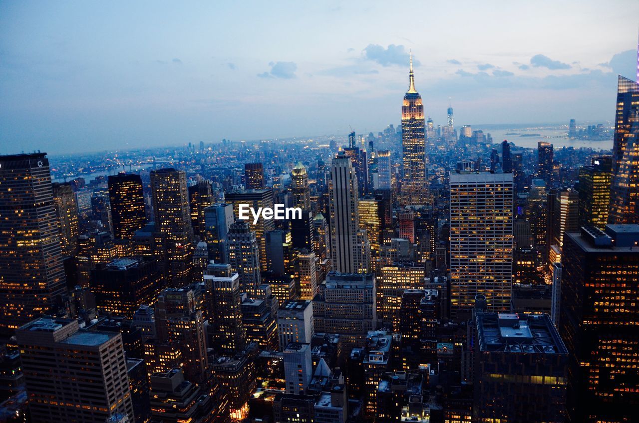 Illuminated cityscape against sky at dusk