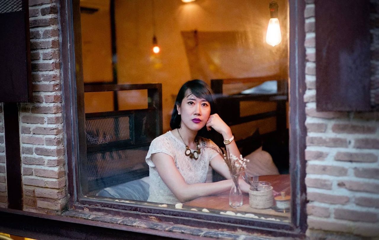 Portrait of mid adult woman sitting in restaurant seen through window