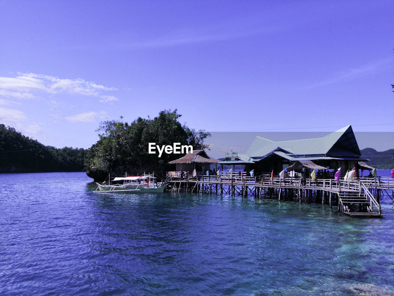 Houses by lake against blue sky