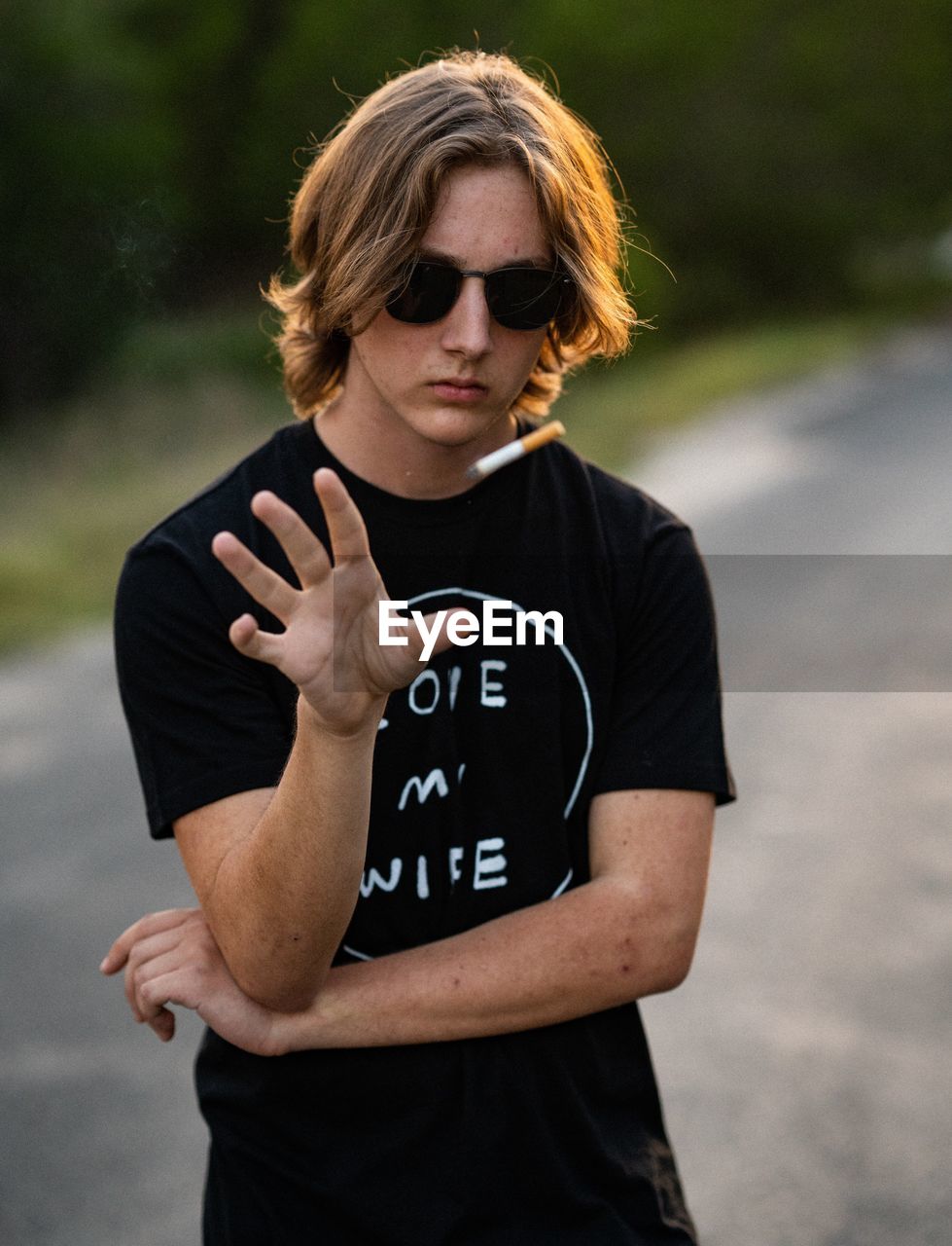 MID ADULT MAN WEARING SUNGLASSES STANDING AGAINST WALL