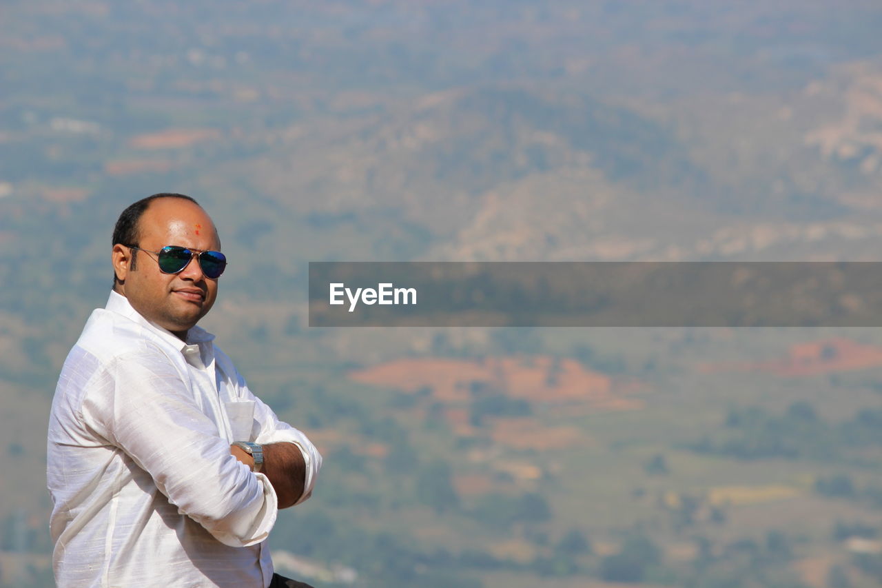 Portrait of man wearing sunglasses against landscape 