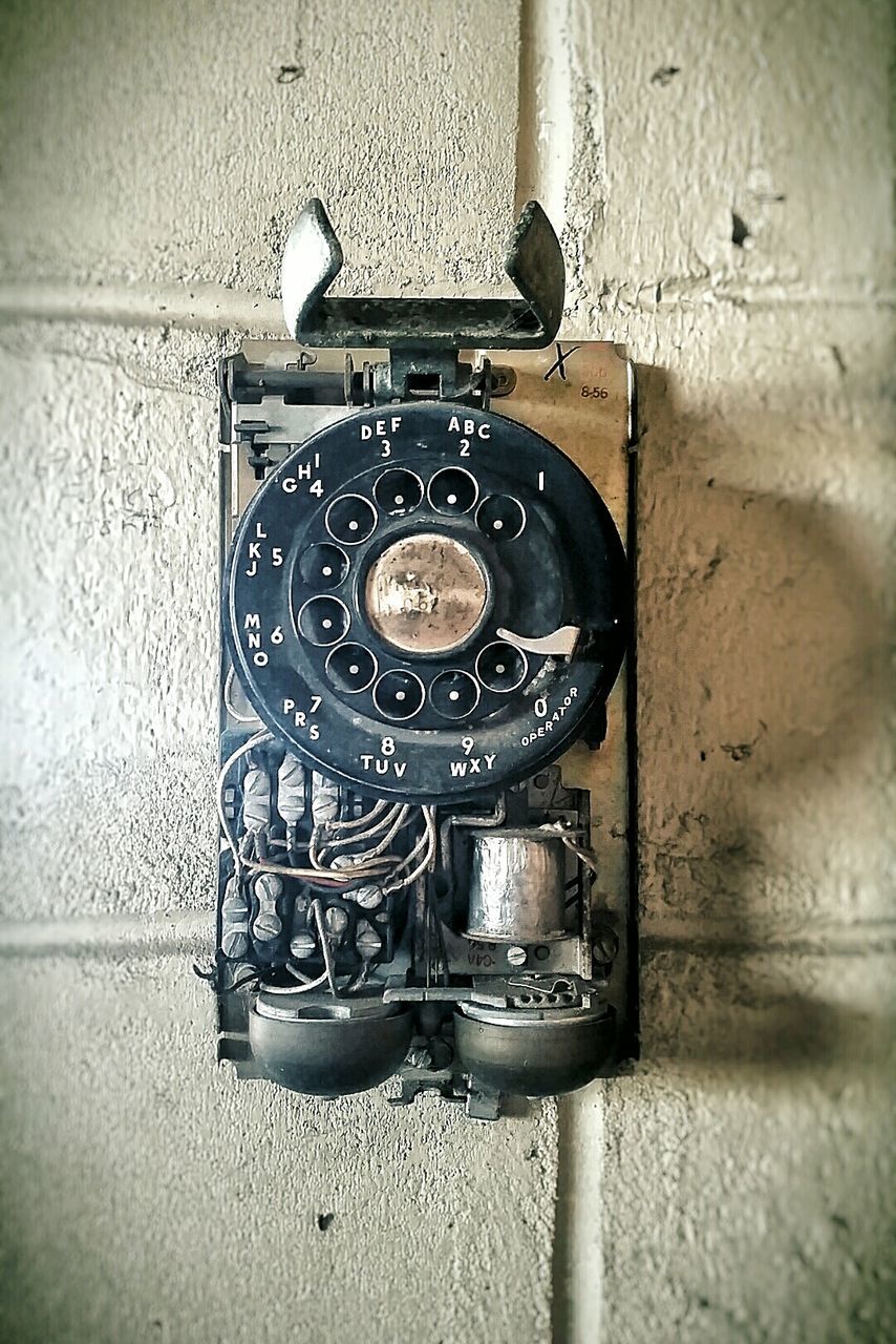 Damaged rotary phone hanging on wall