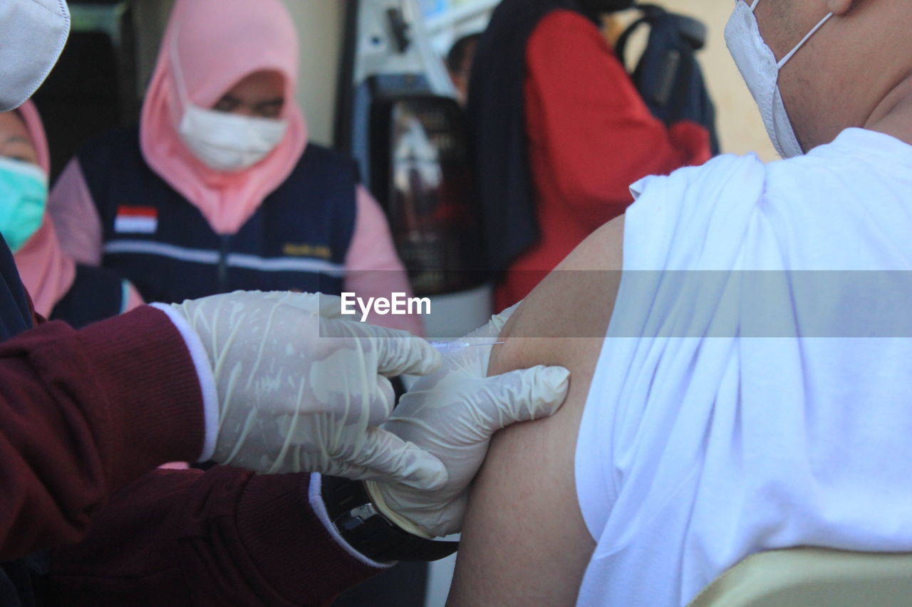 A man is being vaccinated by medic in public vaccination.