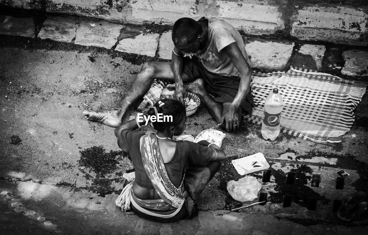 HIGH ANGLE VIEW OF MEN SITTING ON WALL