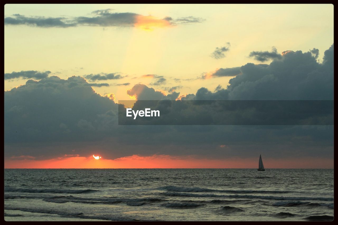 Lone sailboat in calm sea at sunset