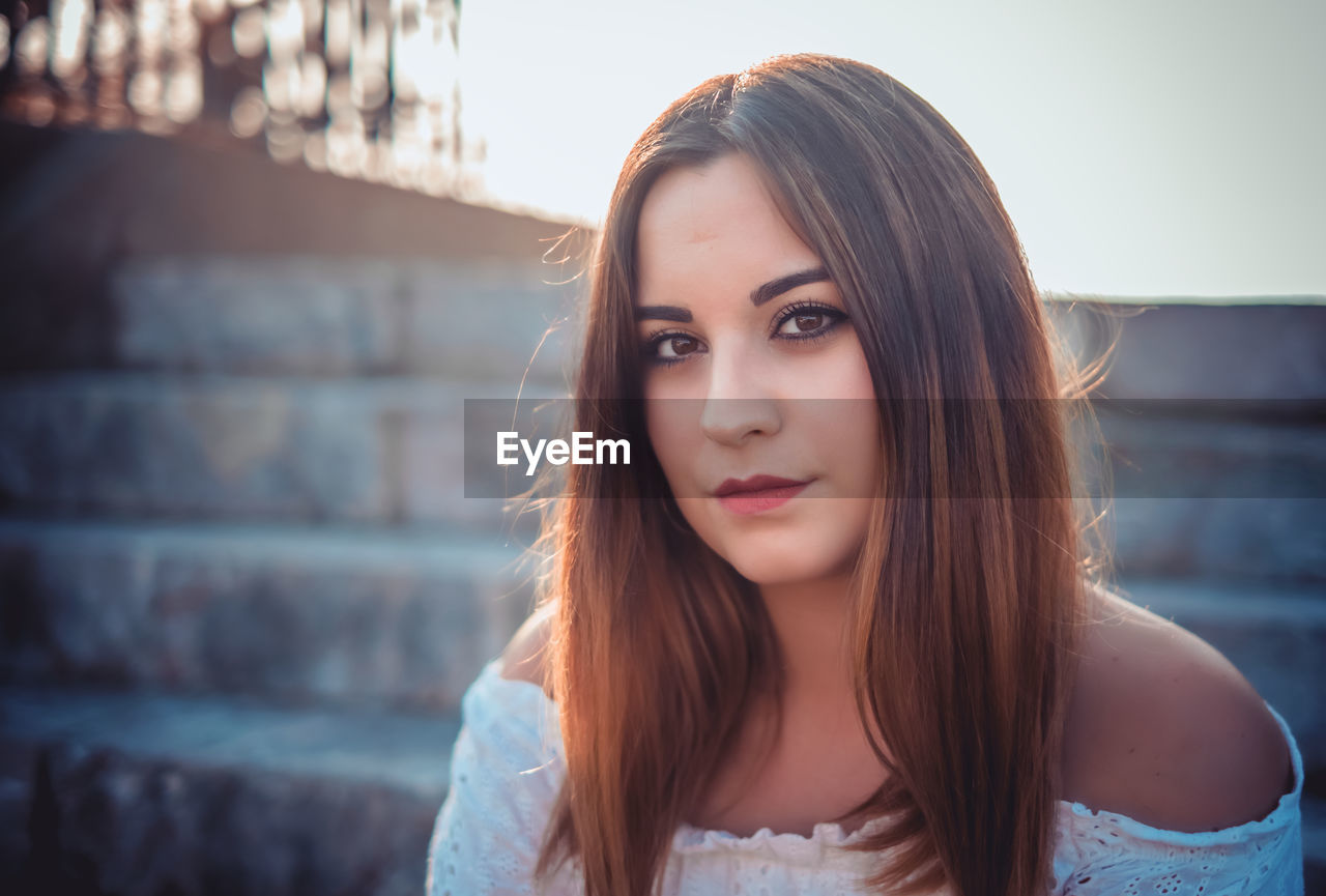 Close-up portrait of a beautiful young woman sitting on steps