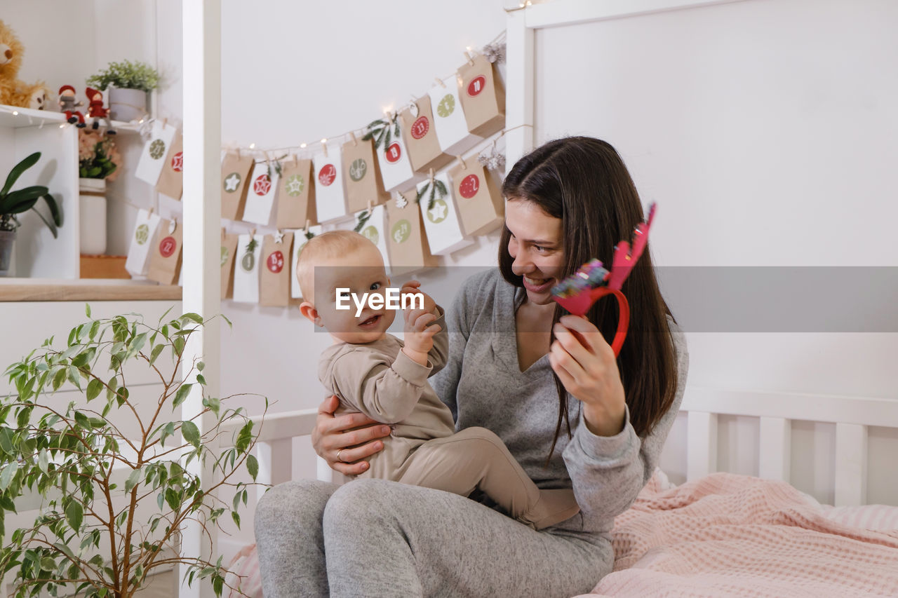 Mother with infant child having fun christmas advent calendar tasks and gifts. baby boy excited