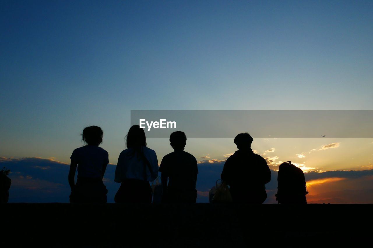 Silhouette people looking at sunset sky