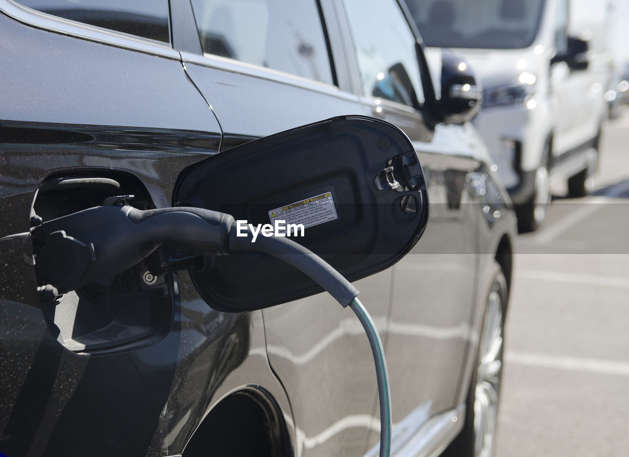 Close-up modern electric commercial van car plugged with fast charger at charging station. eco