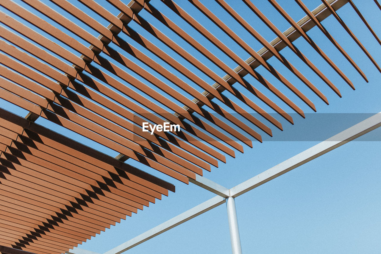 Low angle view of shade structure against clear blue sky