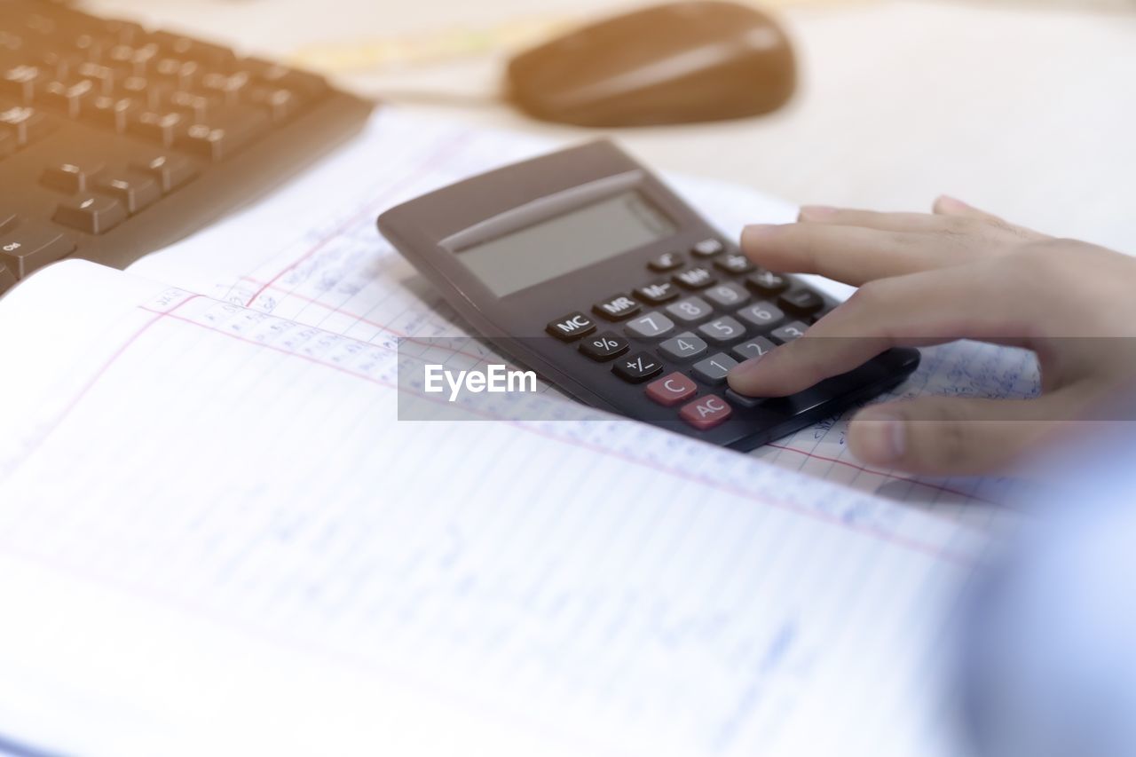 Close-up of person using calculator on table