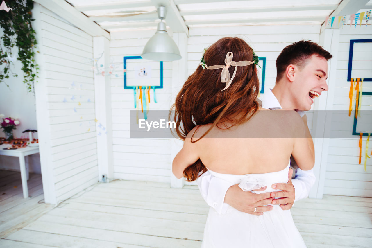 Happy couple embracing while standing at home