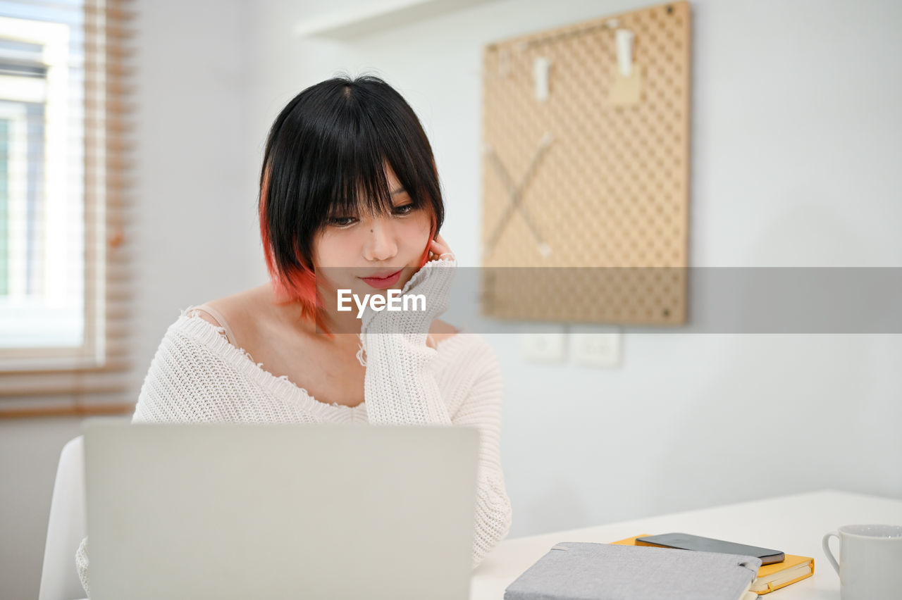 young woman using laptop while sitting at home
