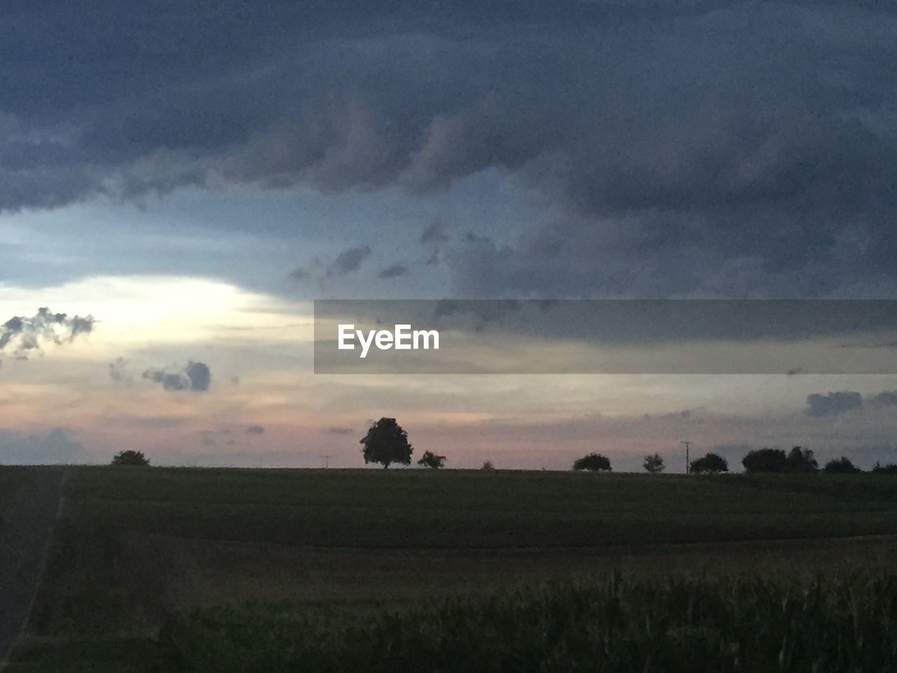 Scenic view of agricultural field against dramatic sky