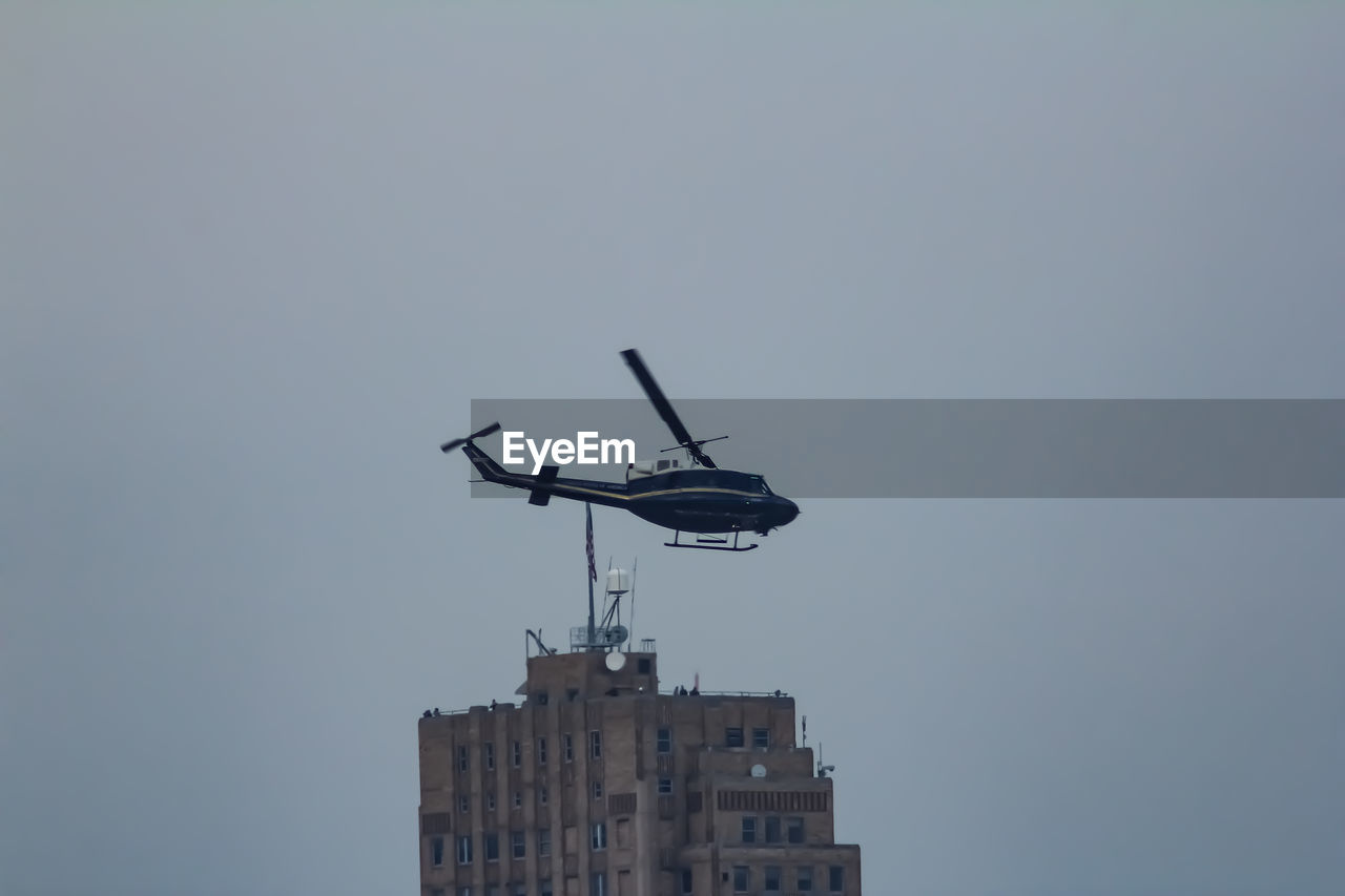 LOW ANGLE VIEW OF AIRPLANE FLYING IN BUILDING AGAINST SKY