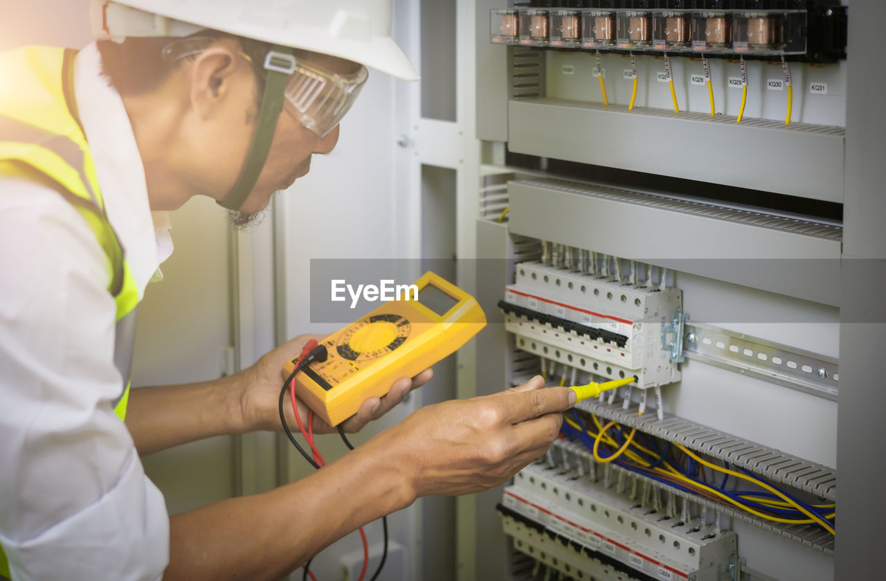 Electrical engineers test the voltage and current of the wires in the electrical cabinet control.
