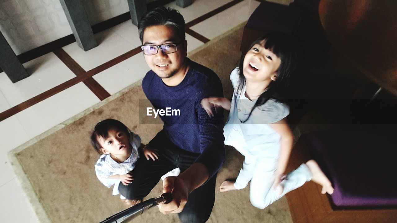 High angle portrait of father with cute daughters at home