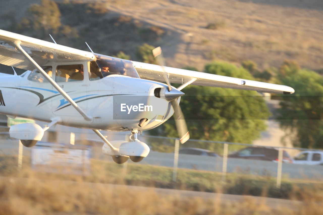 CLOSE-UP OF AIRPLANE FLYING OVER VEHICLE