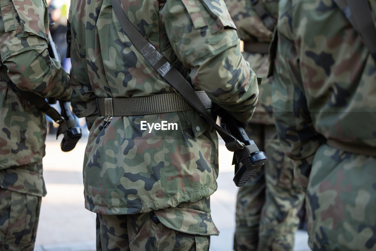 Rear view of soldiers standing in several ranks with weapons.