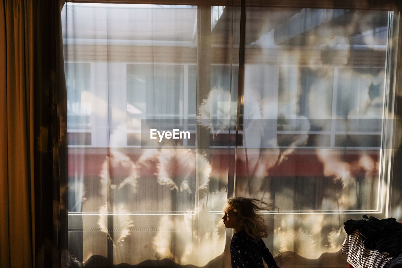 PORTRAIT OF WOMAN LOOKING THROUGH WINDOW