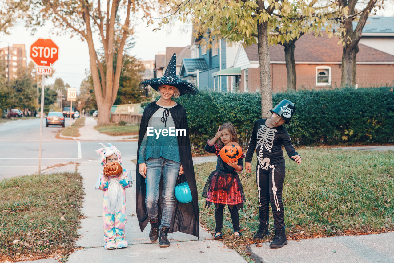 Mother and kids wearing costume standing outdoors