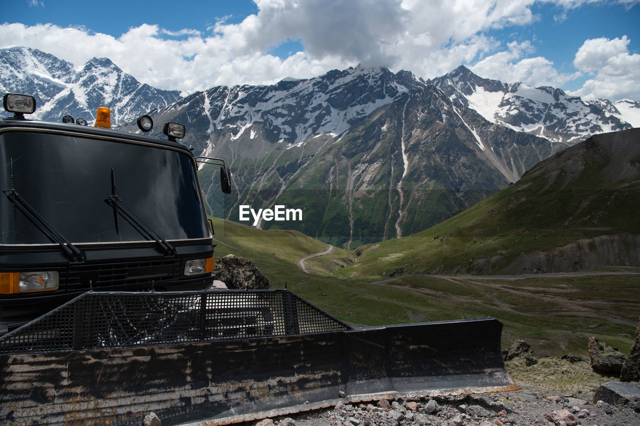 A black grader stands in the mountains in summer.  ratrak, a machine for paving roads in the snow