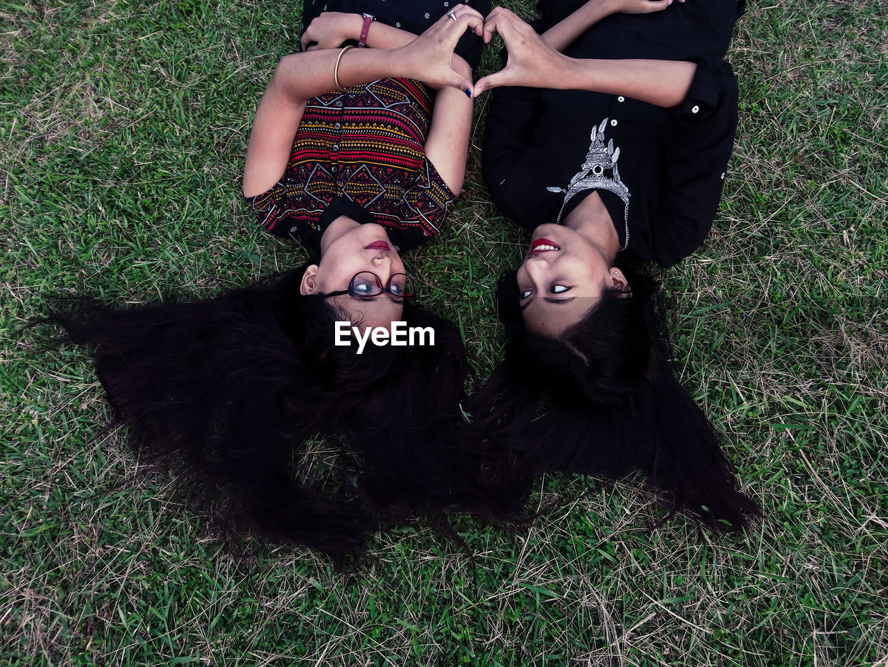 HIGH ANGLE VIEW OF YOUNG WOMAN LYING ON GRASSY FIELD