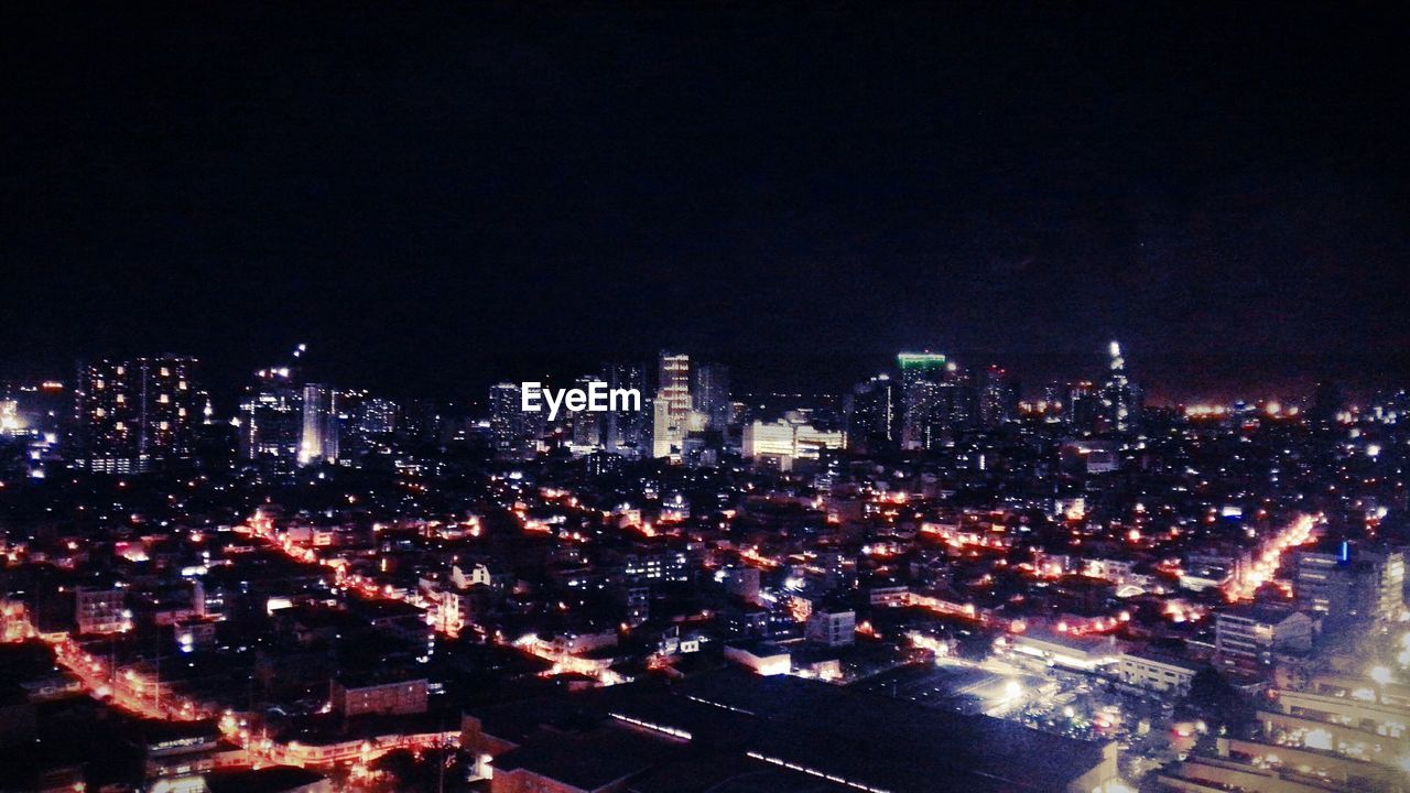 AERIAL VIEW OF ILLUMINATED CITYSCAPE AGAINST SKY