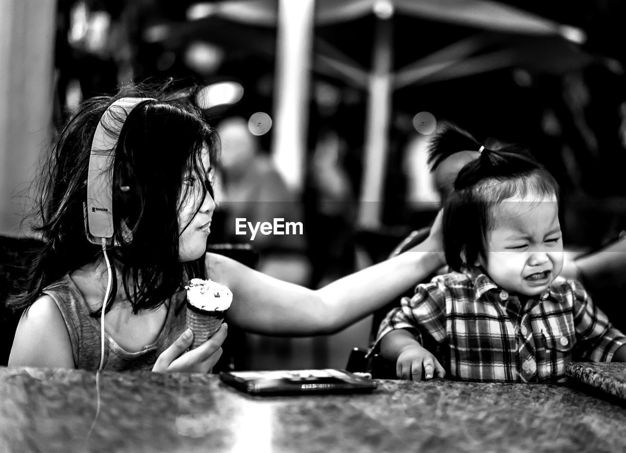 Girl eating ice cream and touching crying brother