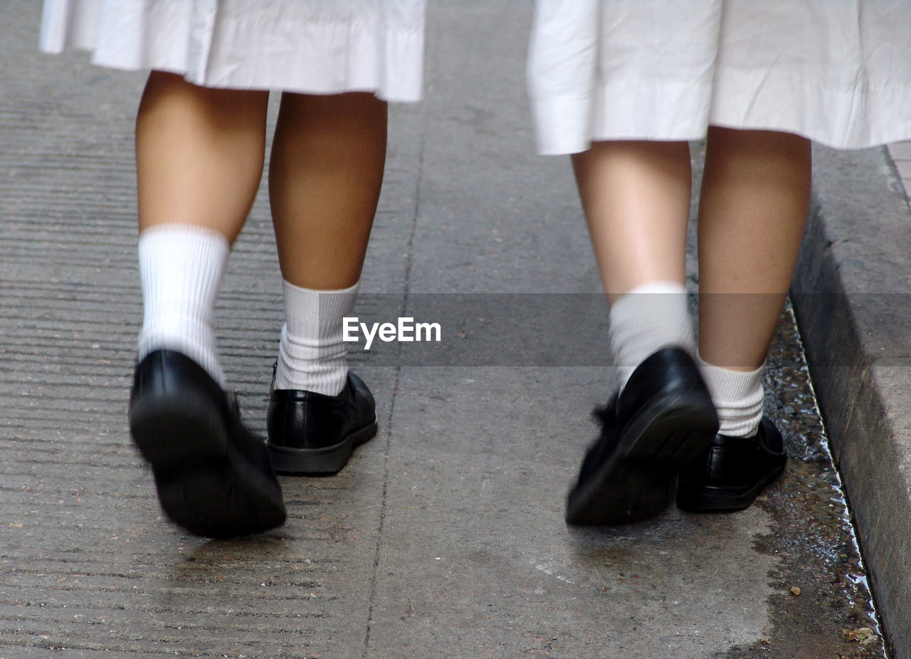 Low section of girls wearing school uniform walking on sidewalk