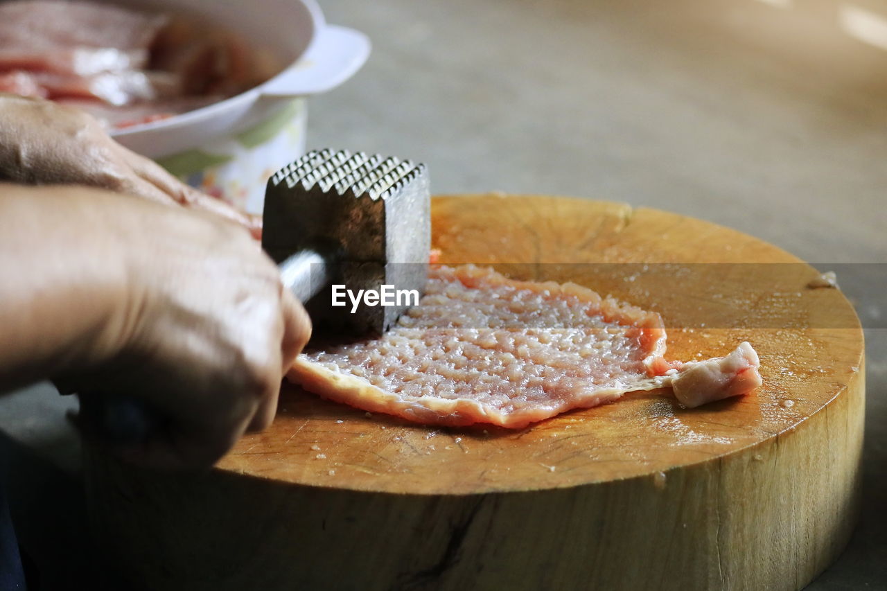 Close-up of hand holding bread on cutting board