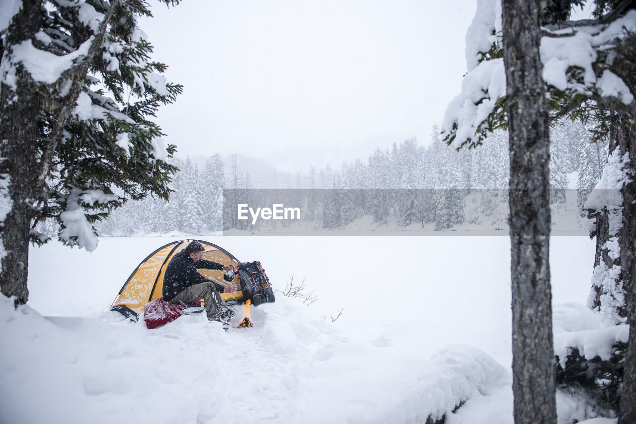 Senior man camping in snow-covered landscape