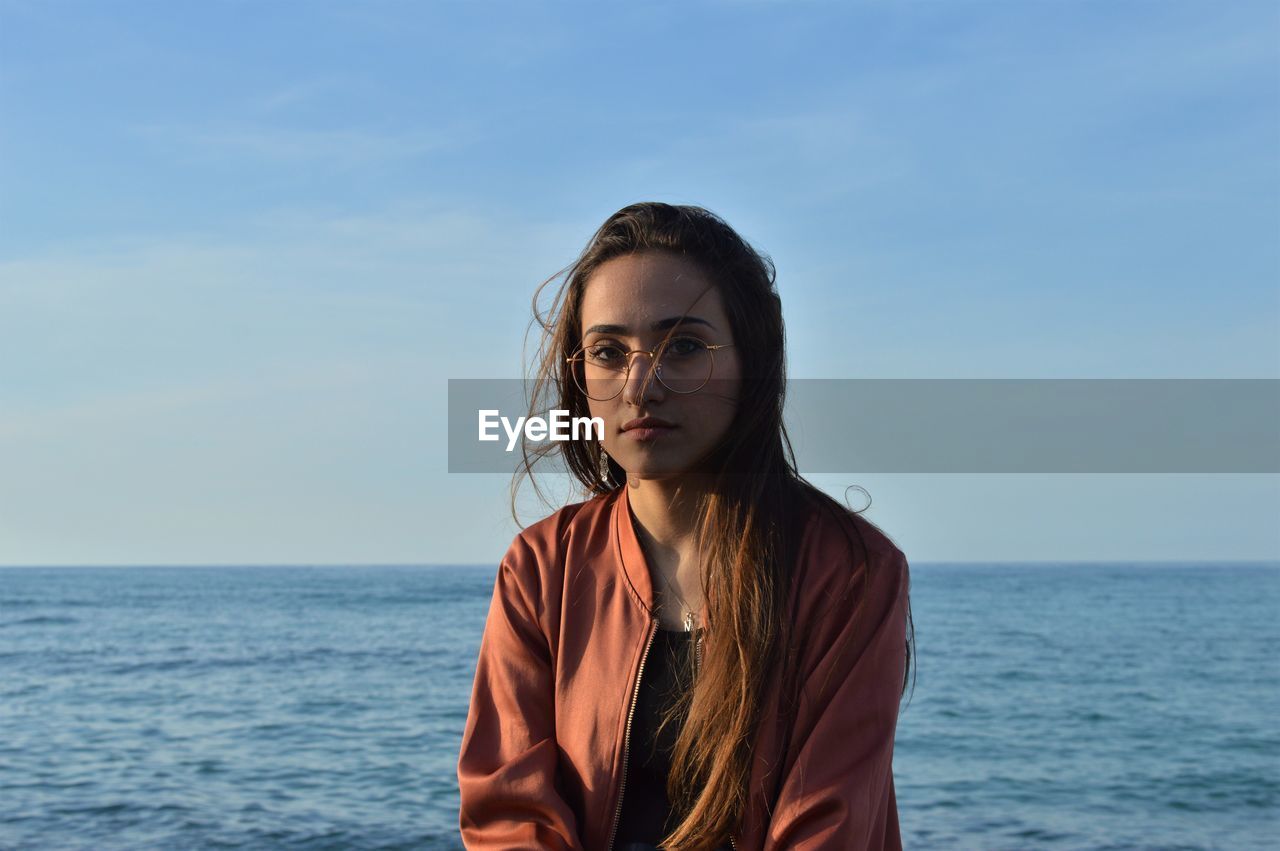 Young woman by sea against sky