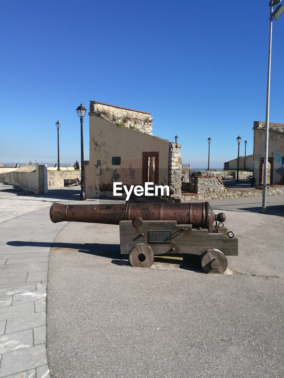 Old cannons on street against clear blue sky