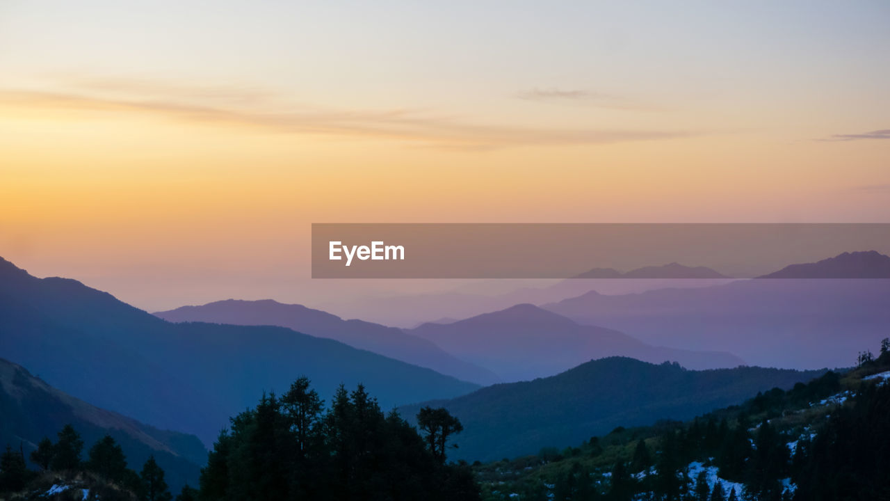 Scenic view of silhouette mountains against orange sky